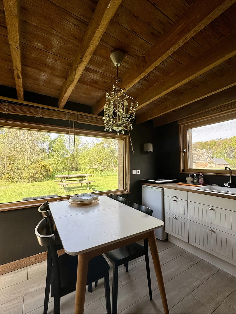 cuisine petite maison de rose Cuisine lumineuse et salle à manger dans un gîte du Domaine de la Ferme de Fourges, avec vue sur le jardin verdoyant et mobilier en bois, typique d’un séjour en Normandie.