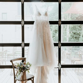 Robe de mariée suspendue dans une verrière lumineuse